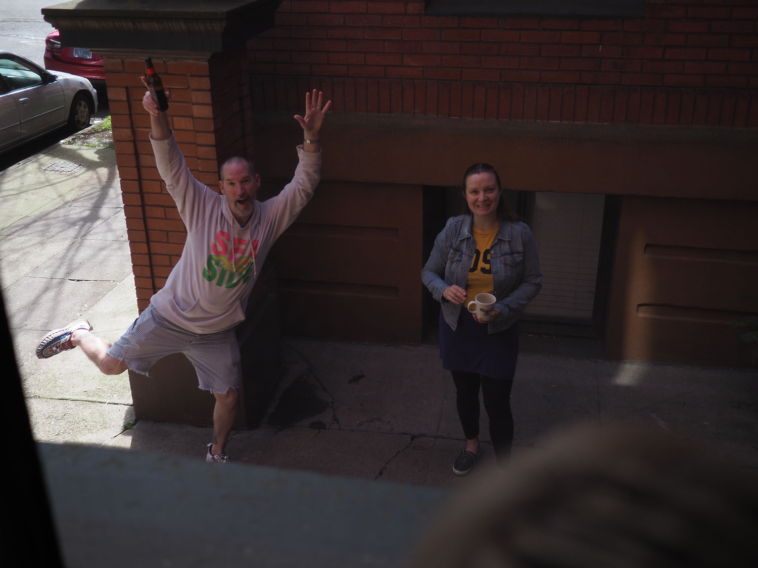 Kirsty and Joe standing in the courtyard. Joe is standing on one foot and holding a beer and Kirsty is smiling.