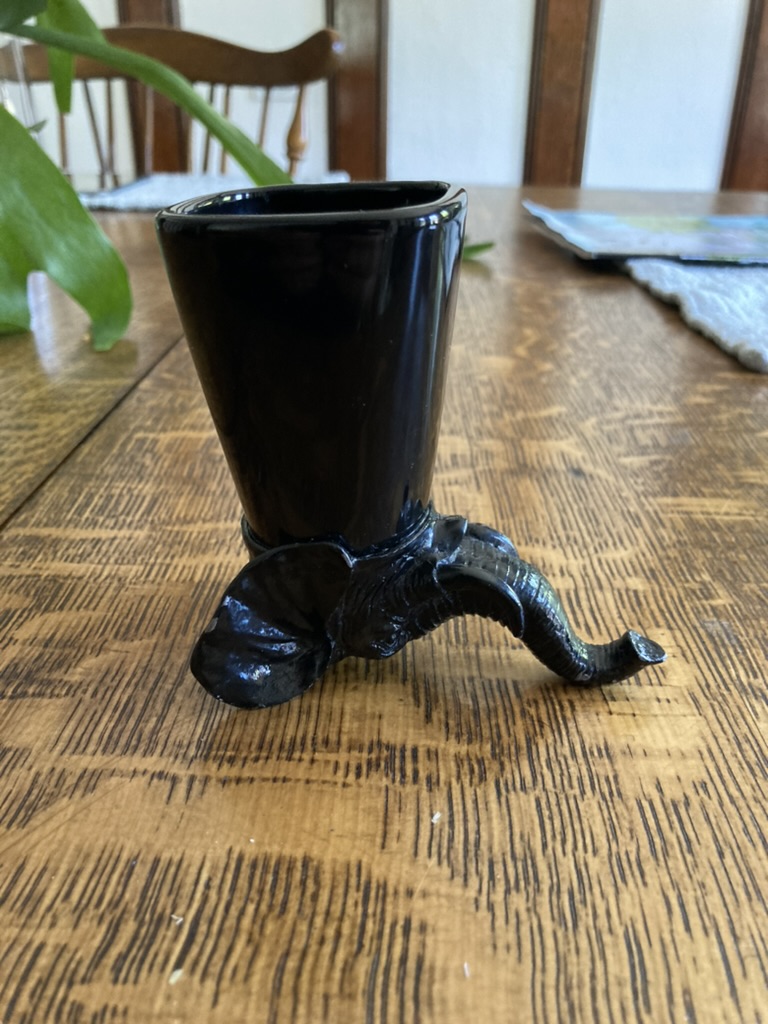 A strange black cup with an iron elephant upside down at the bottom